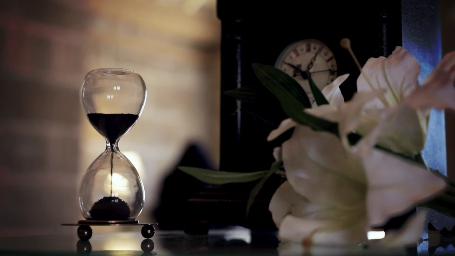 An hourglass, antique clock and white lilies inside the Lilies and Dust escape room