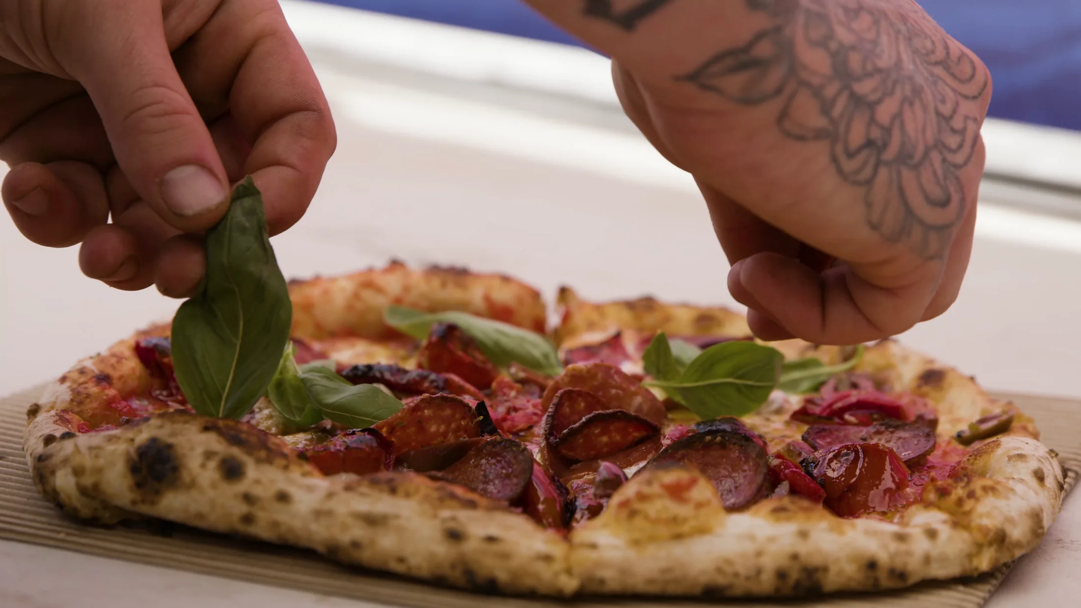 Fresh basil being placed on a White Pearl pizza