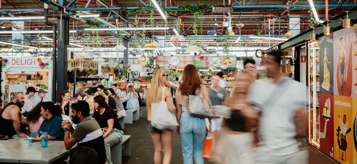 Shoppers and diners moving through the colourful interior of Prahran Market