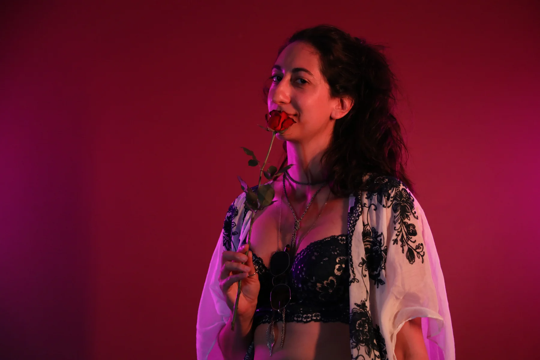 Ella holding a rose against a red backdrop