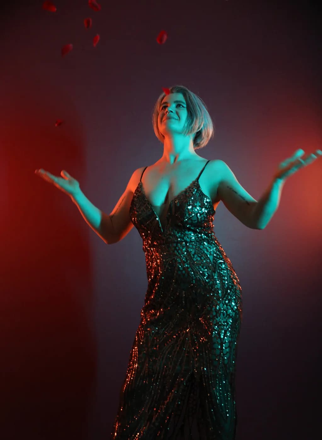 Mercury standing in a sequinned dress under coloured light